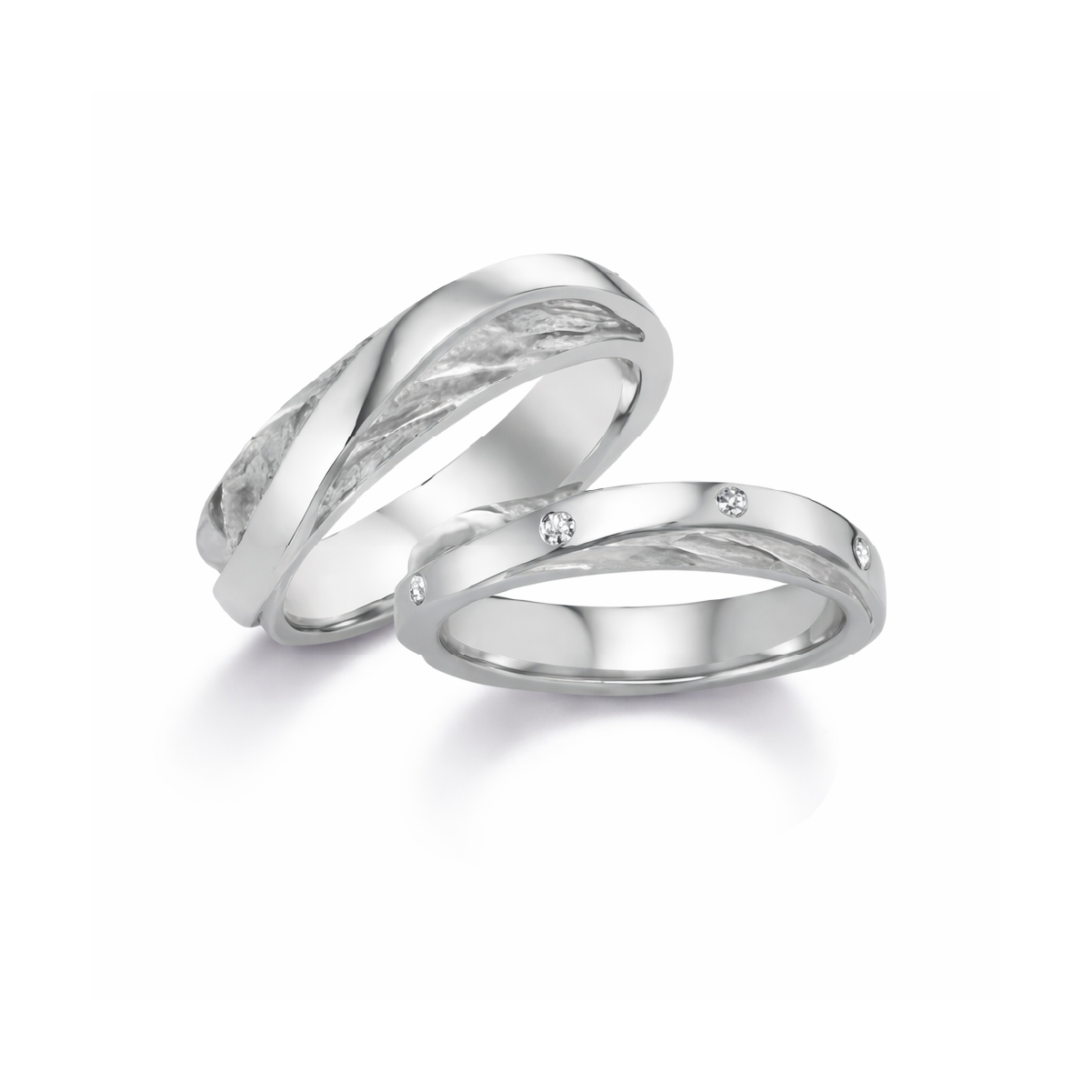 Zwei elegante Eheringe aus Silber mit Diamantakzenten auf weißem Hintergrund, symbolisch für langlebige Liebe.